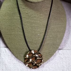 Round goldtone pendant on black cord necklace